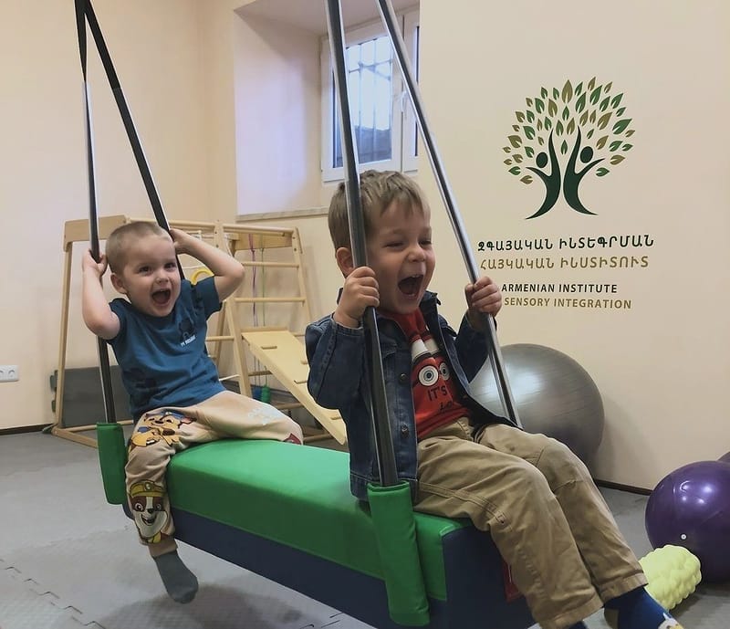 Мальчики качаются на подвесном бревне в сенсорном зале